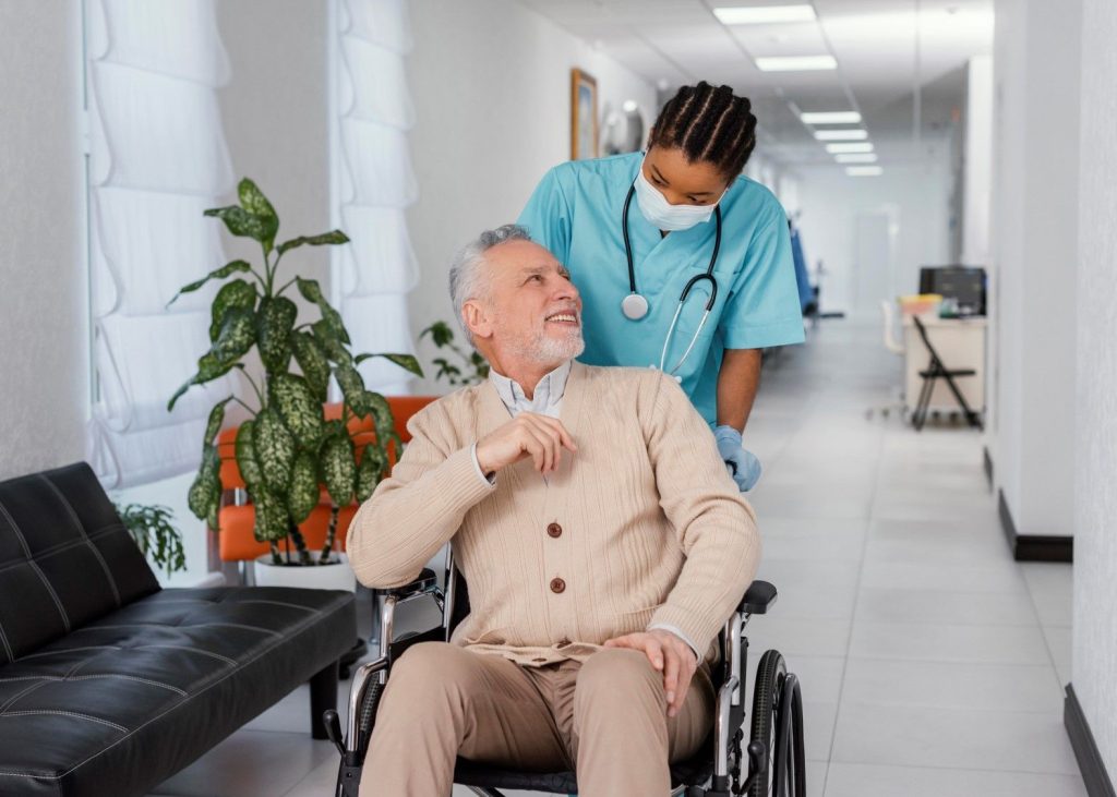 A carer helping a smiling older man in a wheelchair
